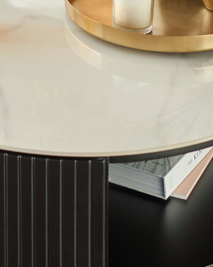 Malachy coffee table with white ceramic top and black fluted base, styled with books and gold accessories.