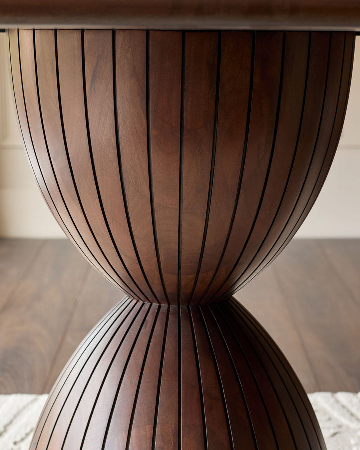 Close-up of Malin dining table base showing dark mango wood with vertical slat details and hourglass silhouette.