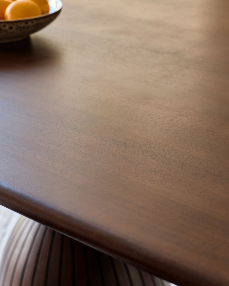 Dark mango wood dining table top with natural grain detail and pleated base visible.