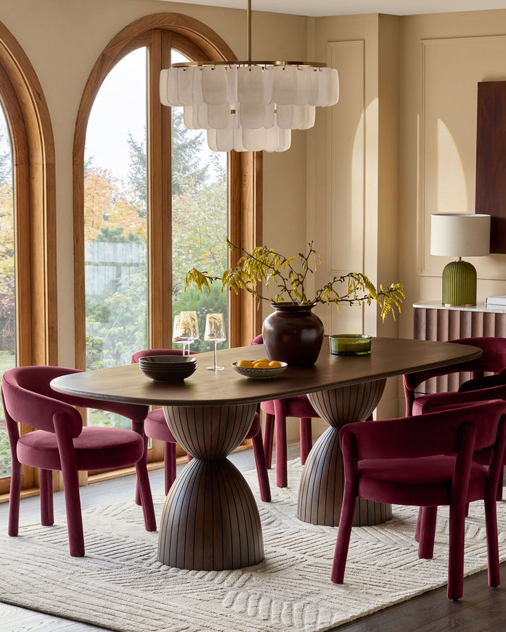 Dark mango wood 8-seater dining table with sculptural fluted base, oval top, shown in modern dining room setting.