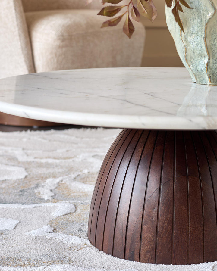 Malin coffee table with white marble top and dark mango wood pedestal base, styled with dried flowers in vase on neutral rug.