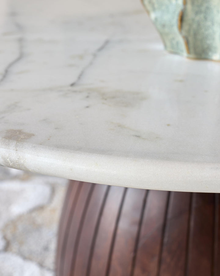 White marble round coffee table top with dark mango wood pedestal base, close-up detail view.