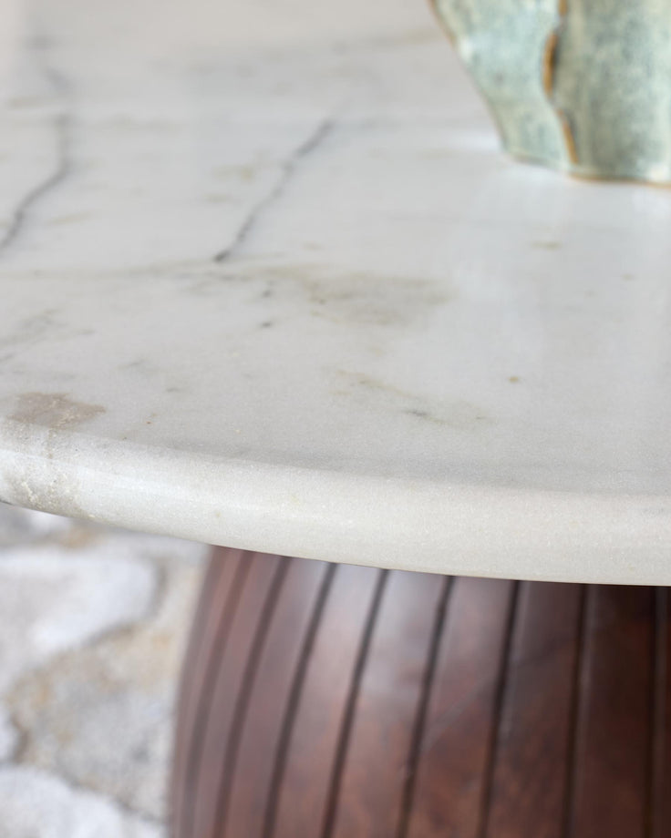 White marble round coffee table top with dark mango wood pedestal base, close-up detail view.