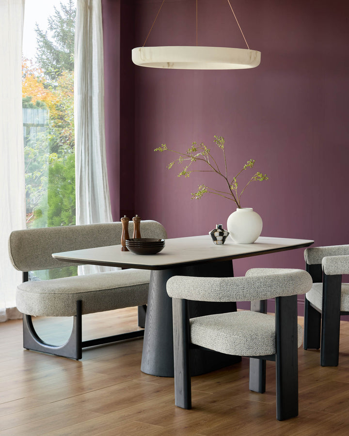 Manhattan 8-seater dining table in ceramic white with black pedestal base, shown with matching upholstered chairs in a modern dining room setting.