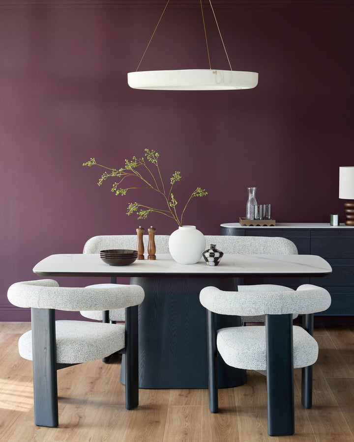 Manhattan 8-seater dining table in ceramic white with black base, paired with curved cream upholstered chairs in modern dining setting.