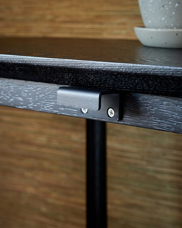 Close up of a black table with a textured top and metal details, displaying modern design.
