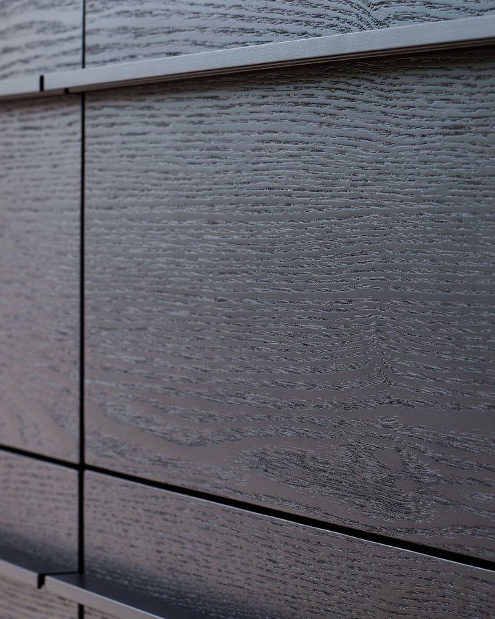 Dark wood-finish drawer chest showing textured grain detail and sleek metal handles on stacked drawers.