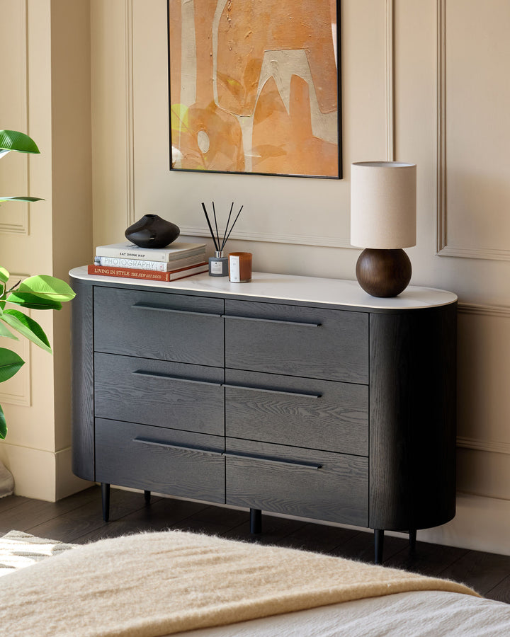 Manhattan 6-Drawer Chest in dark charcoal wood with white ceramic top, rounded corners, black handles, and tapered legs.