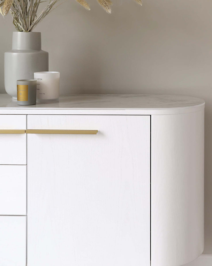 Elegant white curved sideboard with minimalist design, featuring sleek golden handles on its drawers and doors.