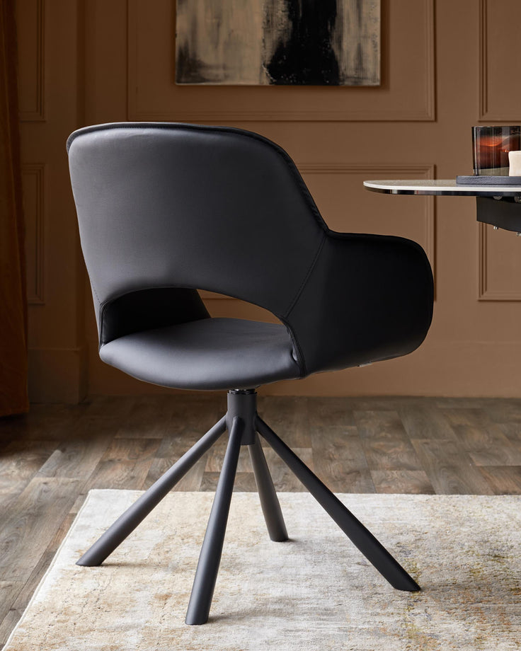 A black, modern swivel chair with a sleek design and metal legs, positioned on a patterned rug.
