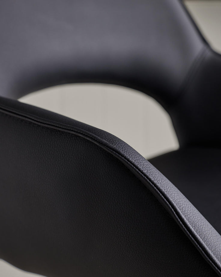 Close-up of a sleek, black leather chair showcasing the texture and curved design of the seat and backrest.