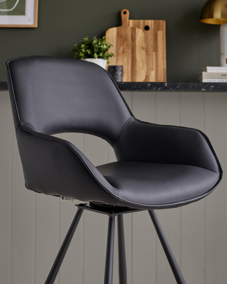 Contemporary black swivel bar stool with a faux leather seat and curved back, on black metal legs.