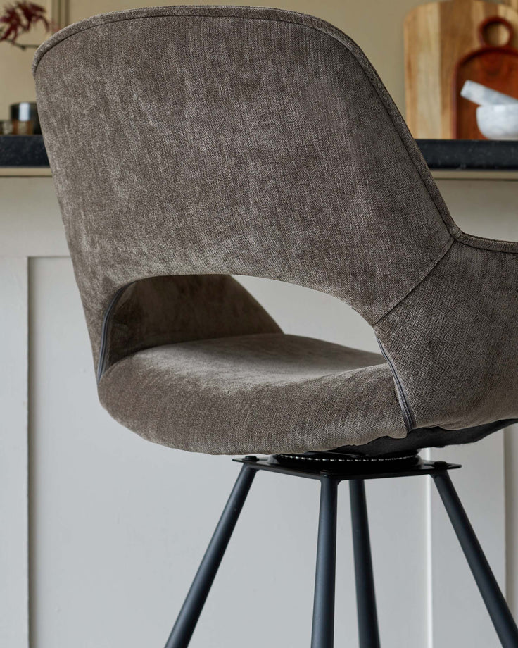 A stylish, grey upholstered bar stool with black metal legs, adding a touch of modern elegance to any kitchen or bar area.