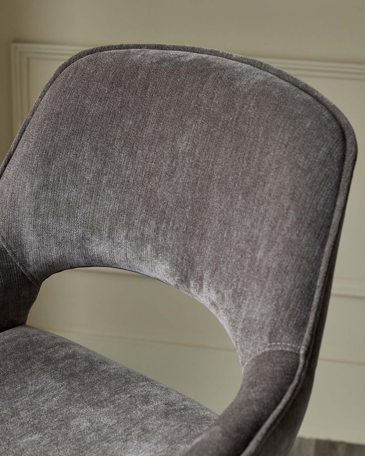 Close-up of a brown upholstered chair, showcasing its curved backrest and plush fabric.