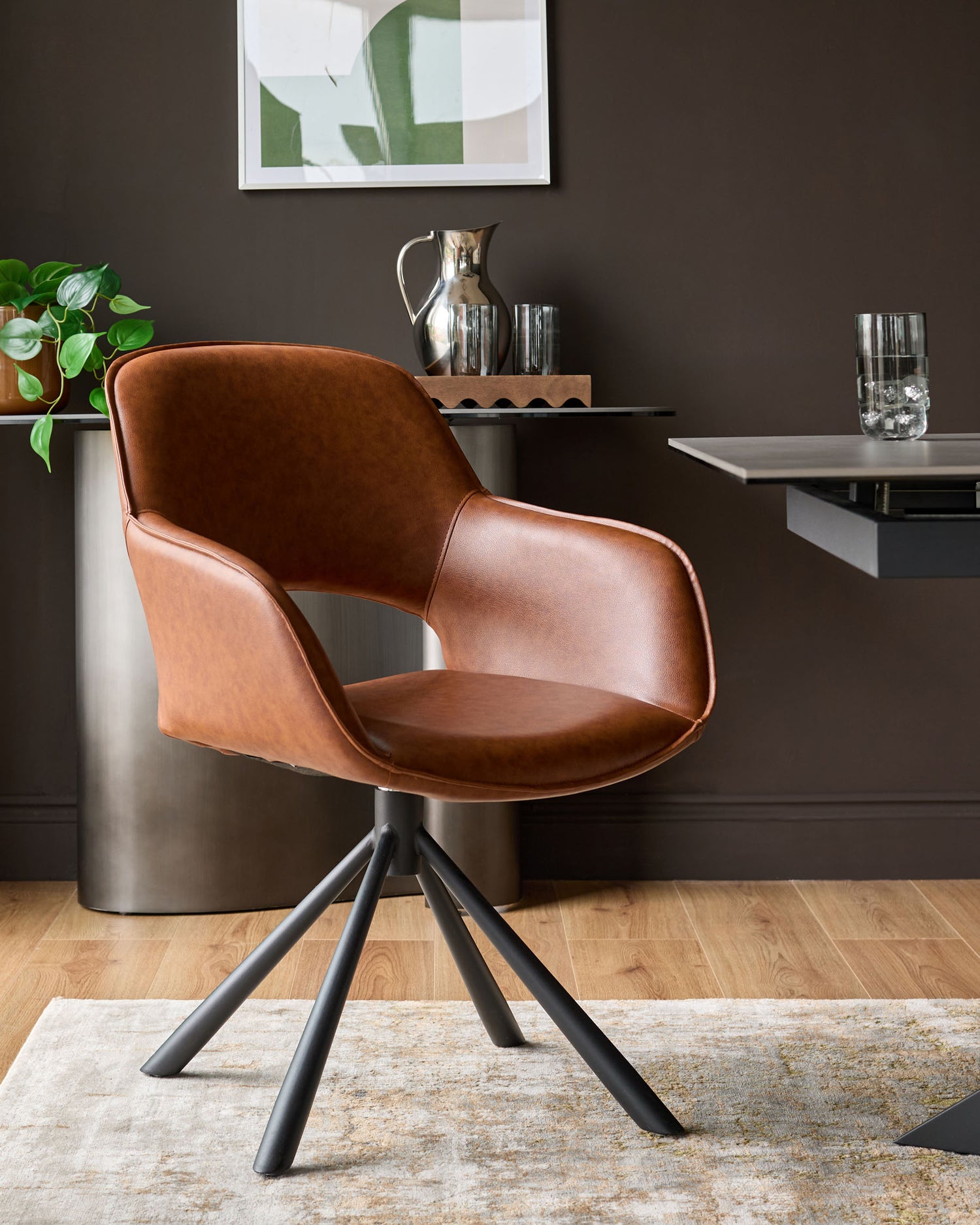 Tan leather swivel dining armchair with curved back, black metal four-leg base, shown in modern office setting.