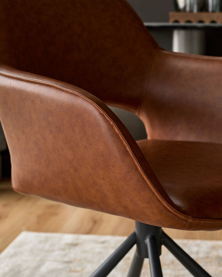 Tan leather swivel dining armchair with curved backrest and black metal base, shown from side angle.