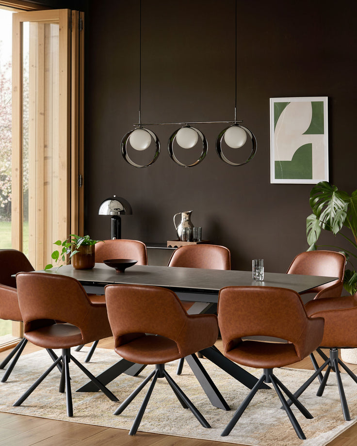 Hayden extending dining table in light grey ceramic with black metal base, shown in styled dining room setting with cognac leather chairs.