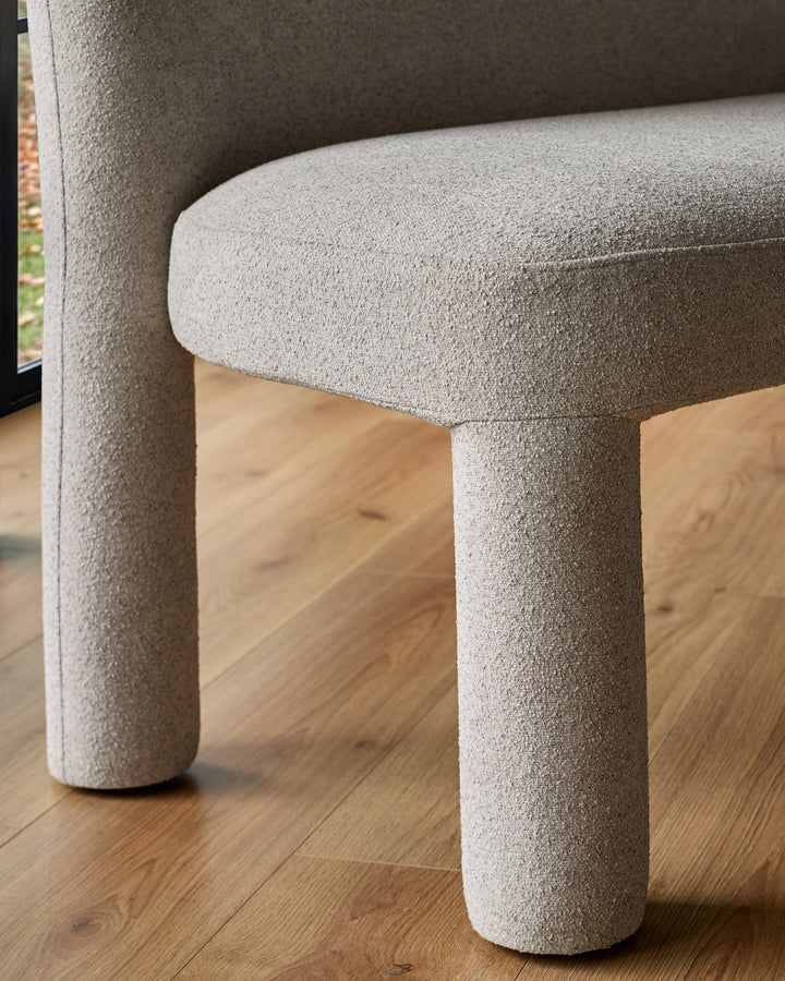 Mason 3-seater dining bench in light grey boucle, showing curved cylindrical legs and rounded armrest detail.