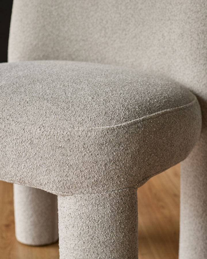 Mason dining chair in light grey boucle, close-up detail of curved seat and cylindrical leg base.