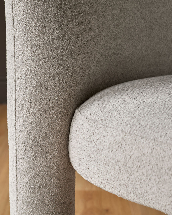 Mason dining chair in light grey boucle, close-up of curved backrest and seat detail.