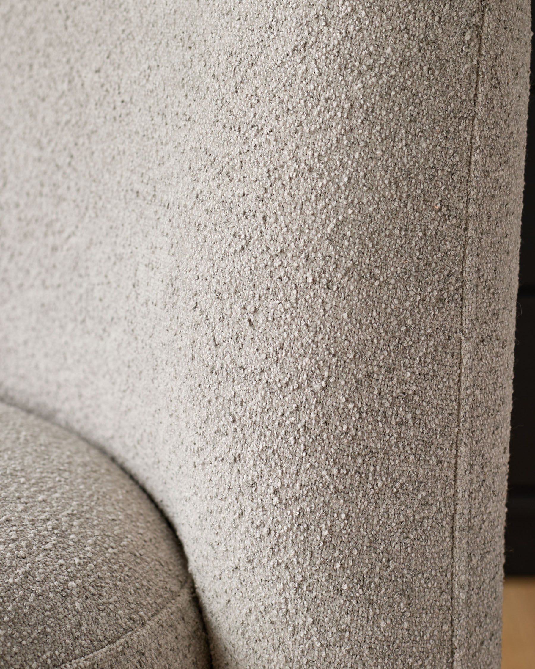 Close-up of light grey boucle upholstery on Mason dining chair, showing textured fabric weave and curved seam detail.