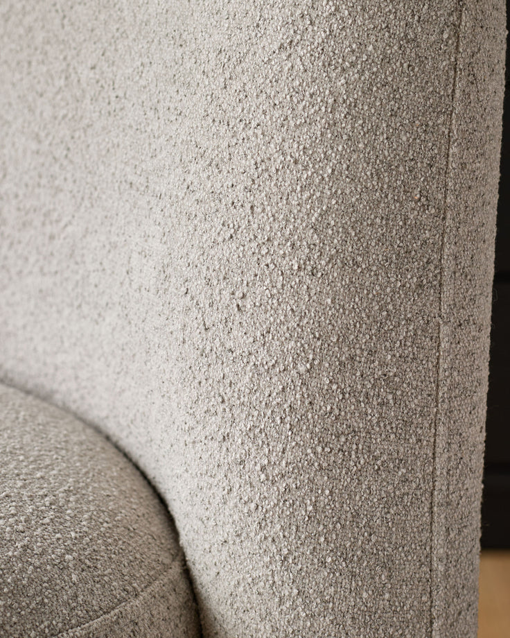 Close-up of light grey boucle upholstery on Mason dining chair, showing textured fabric weave and curved seam detail.