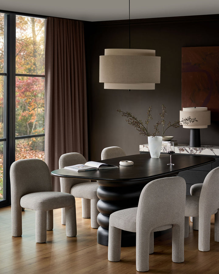 Mason dining chair in light grey boucle fabric with curved cylindrical legs, shown around a black dining table.