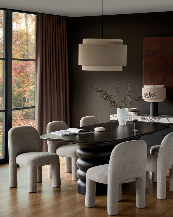 Mason dining chair in light grey boucle fabric with curved cylindrical legs, shown around a black dining table.