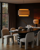 Mason dining chair in light grey boucle, shown in a styled dining room setting around a black table.