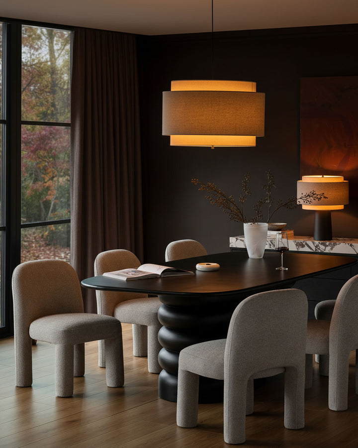 Mason dining chair in light grey boucle, shown in a styled dining room setting around a black table.