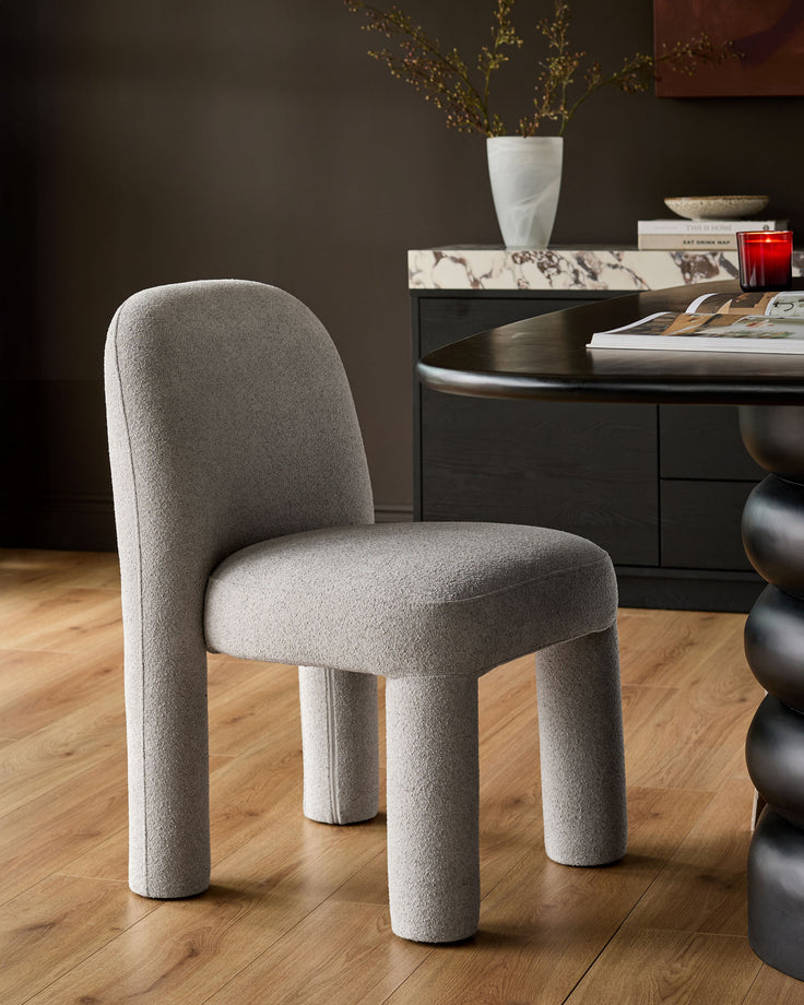 Mason dining chair in light grey boucle fabric, shown from front angle with rounded cylindrical legs and curved backrest.