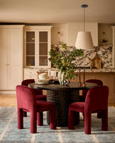 Mason dining chair in plum velvet, shown in a dining space with a round black table and pendant light.
