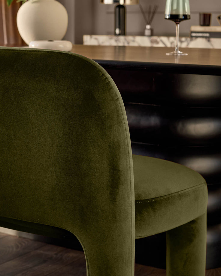 Olive green velvet dining bench with curved backrest, shown in modern dining room setting with black table.