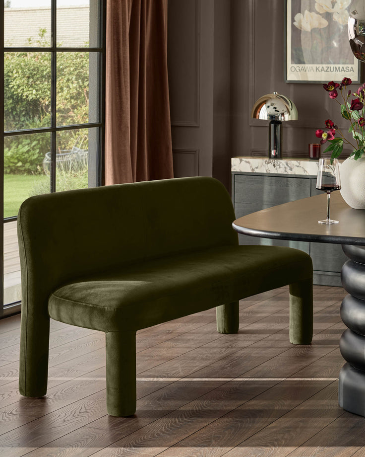 Mason 3-seater dining bench in olive green velvet with rounded cylindrical legs, displayed in a modern dining room setting.