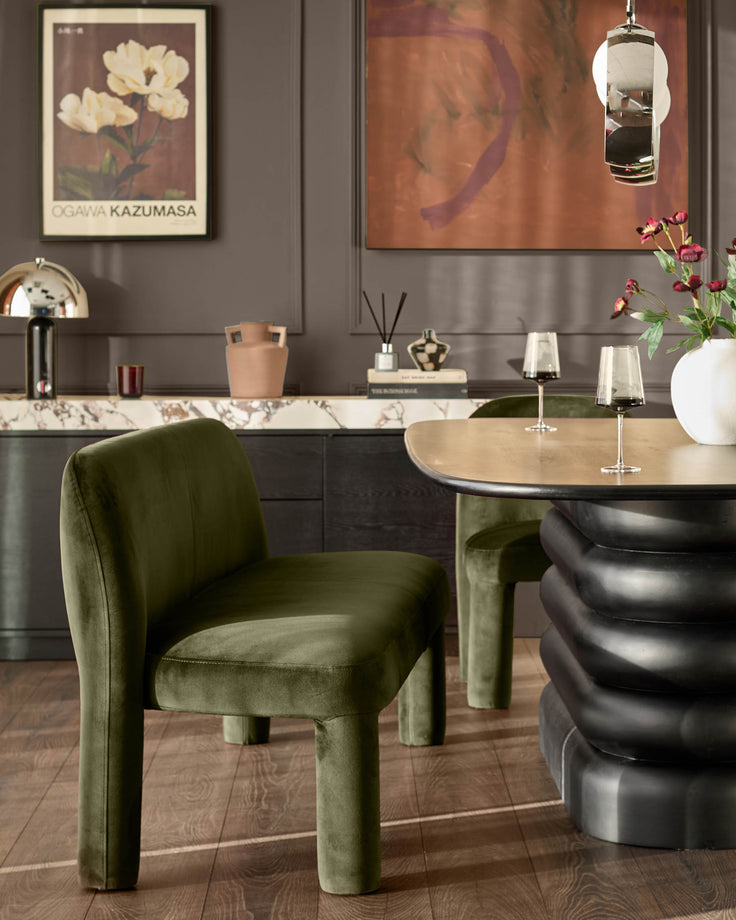 Olive green velvet dining chair with chunky legs in modern interior setting with round table.