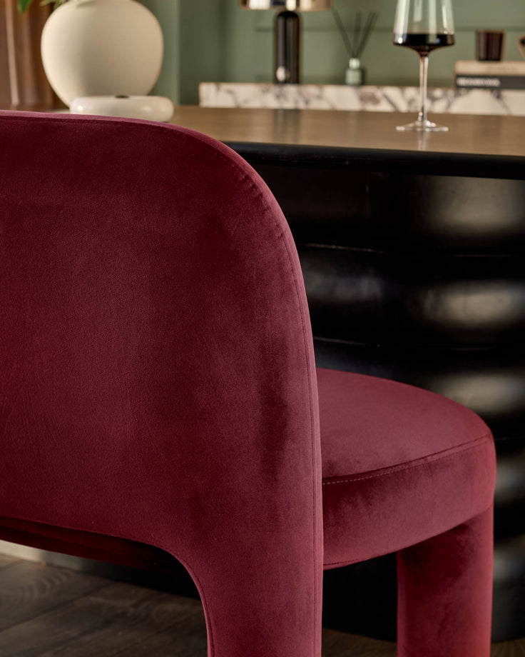Plum velvet dining bench with curved backrest, shown in close-up side view at dining table.