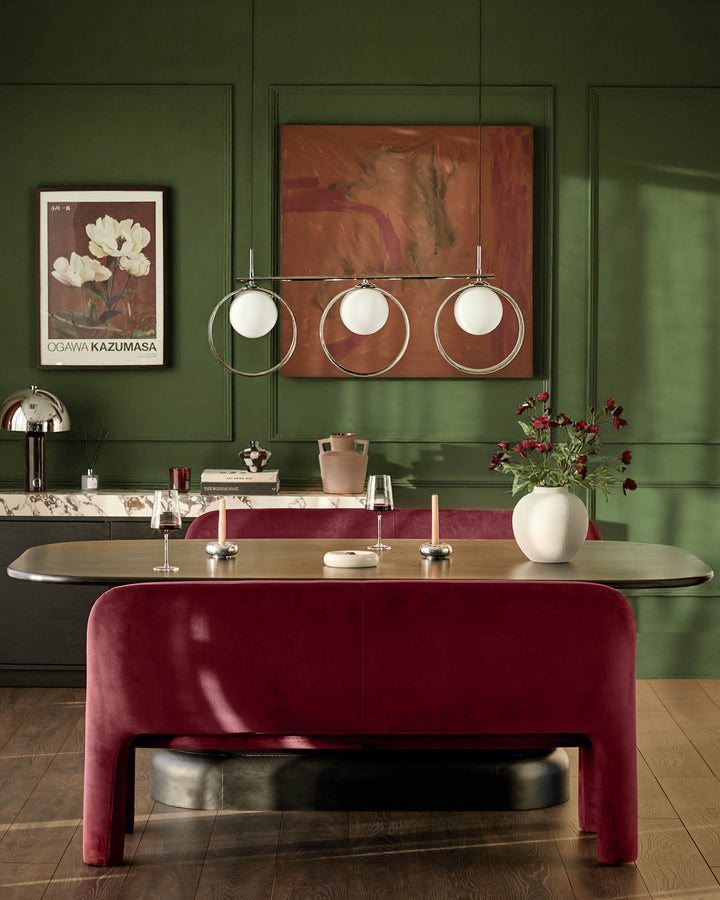 Mason 3-seater dining bench in plum velvet, shown in elegant green dining room setting with curved seat and rounded legs.