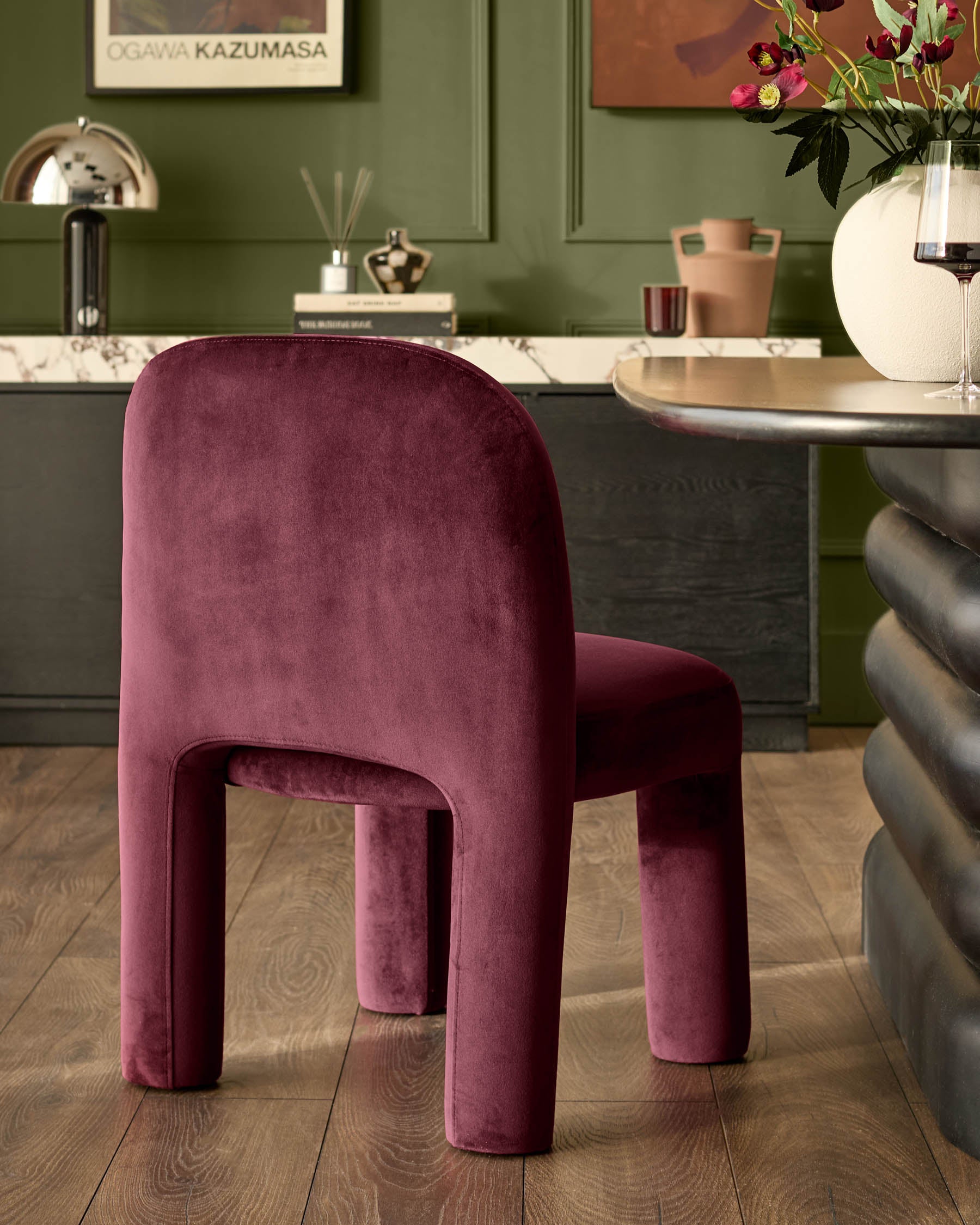 Mason dining chair in plum velvet, shown in a modern interior setting at a curved desk.