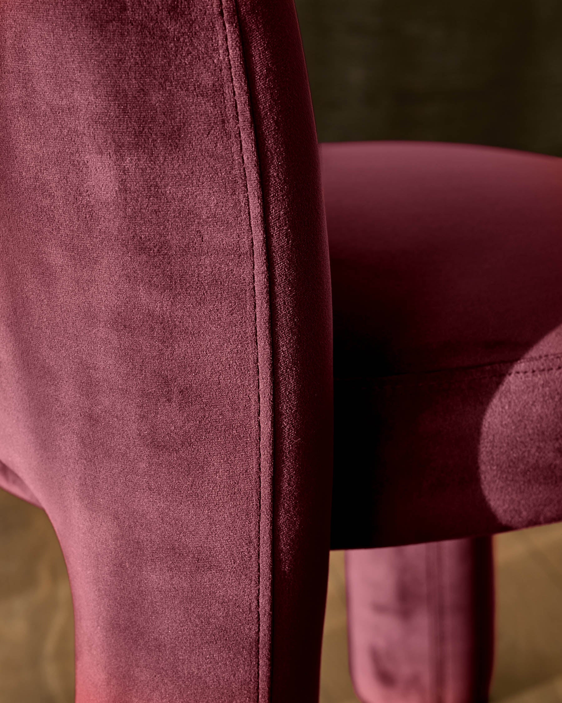 Mason dining chair in plum velvet, close-up detail of seam and upholstery texture with wooden leg visible.