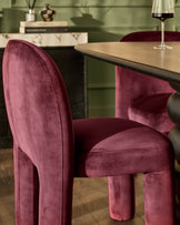 Mason dining chair in plum velvet, shown in a styled dining room setting with matching chair and wine glass.