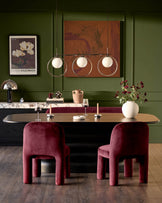 Mason dining chair in plum velvet with curved cylindrical backrest and legs, shown in styled dining room setting.