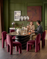 Mason dining chair in rich plum velvet, shown in styled dining room setting around black table.