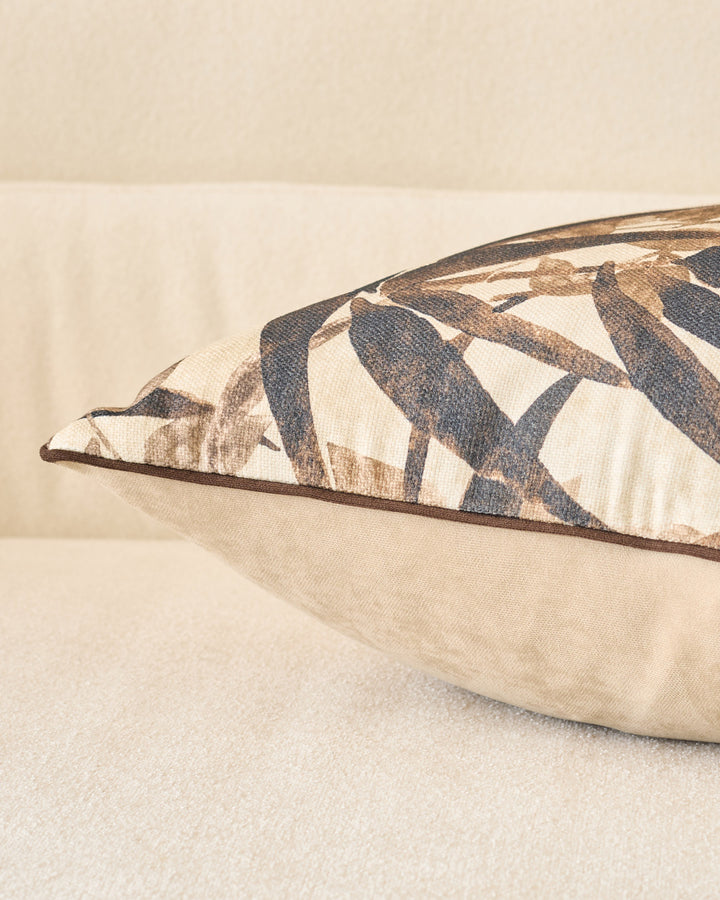 Madeira cushion in natural tones with geometric diamond pattern, shown at an angle displaying its piping detail and plush form.