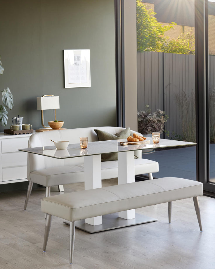 A modern dining table with bench and sofa seating in a neutral colour scheme. Perfect for a contemporary dining space.