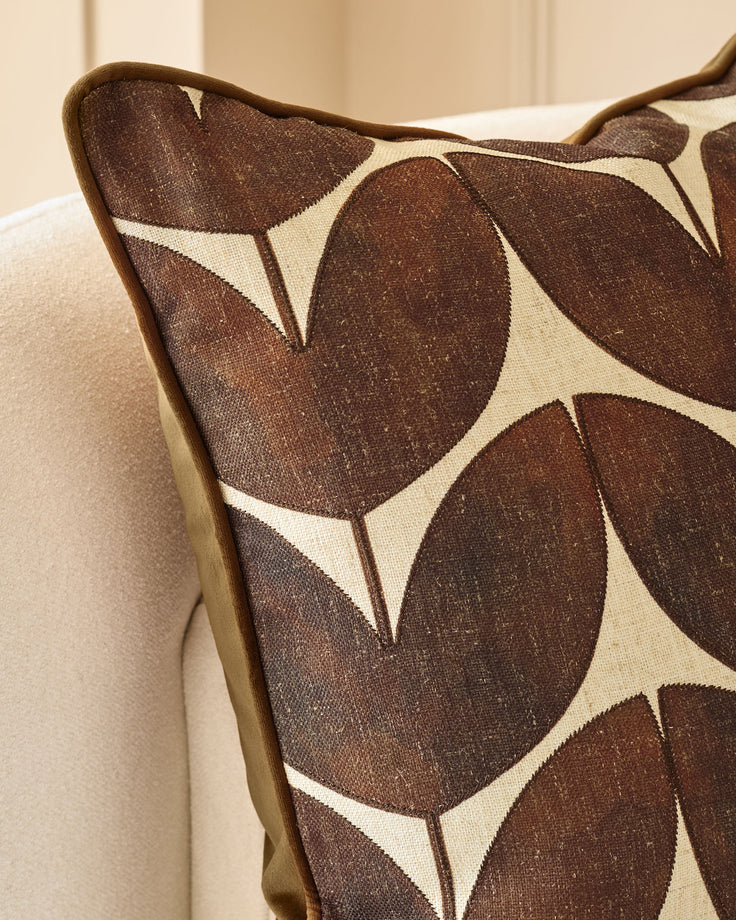 Micah Cushion in chocolate brown with cream geometric leaf pattern, piped edge detail, displayed on neutral sofa.