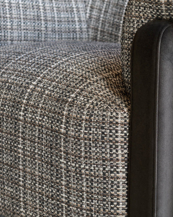 Close-up of Miles Occasional Chair showing Grey textured fabric upholstery and black leather armrest detail.