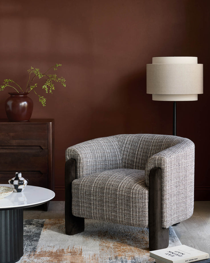 Miles occasional chair in grey textured fabric with dark wooden arms and legs, shown in a styled living room setting.