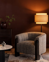 Miles occasional chair in dark chocolate velvet, curved barrel shape with black wooden legs, displayed in warm-lit interior setting.