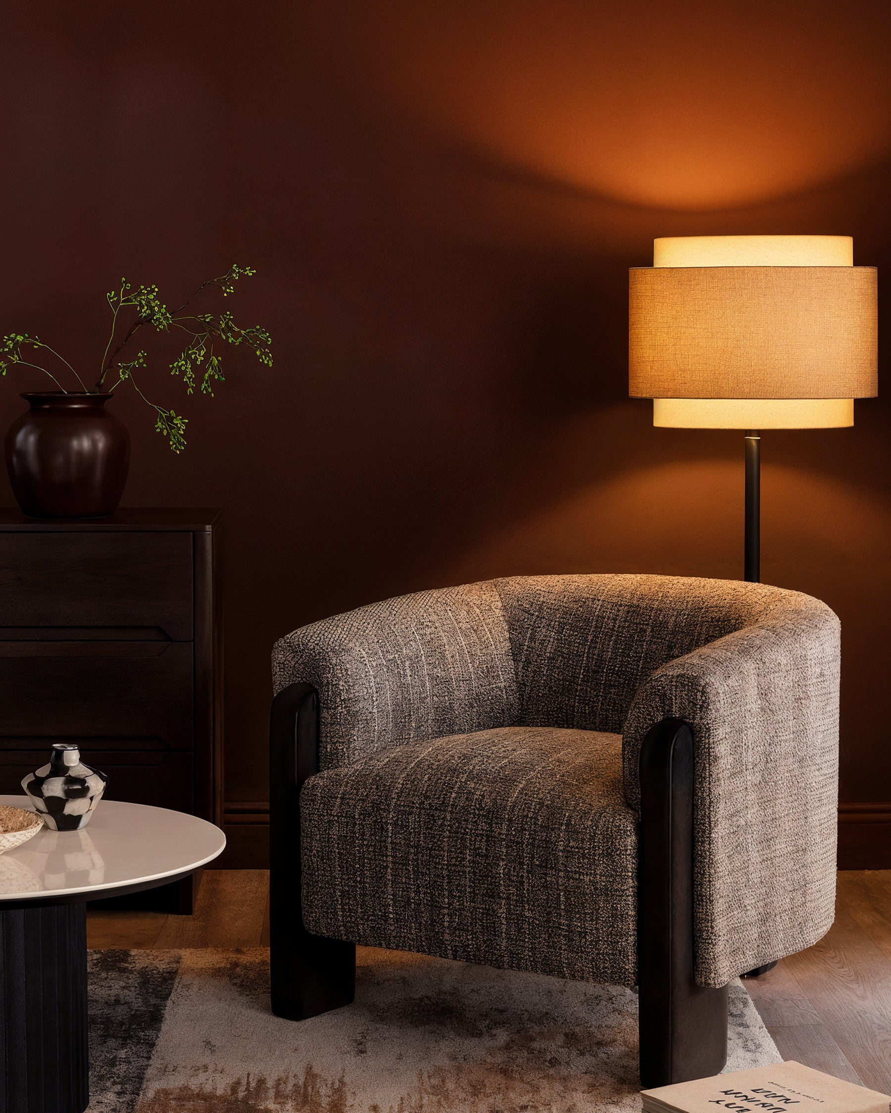 Miles occasional chair in dark chocolate velvet, curved barrel shape with black wooden legs, displayed in warm-lit interior setting.