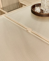 Cream ribbed dining table with integrated circular handle detail, glass top visible, modern minimalist design.